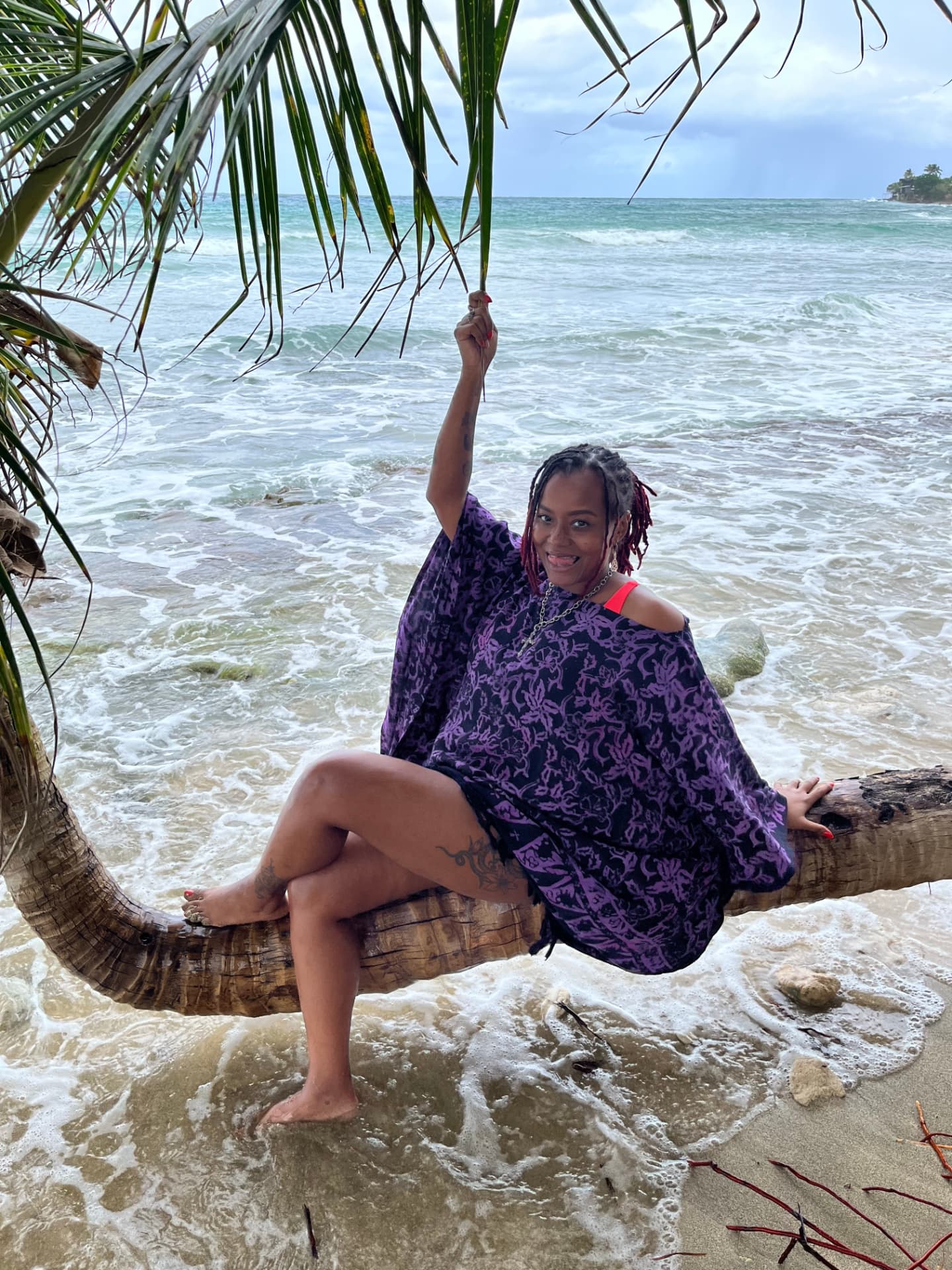 Aly sitting on a fallen palm tree over the sea